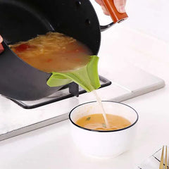 Person using a green ladle to pour soup from a black pot into a white bowl on a stove.