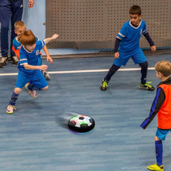Children playing with a hover ball on a blue indoor court