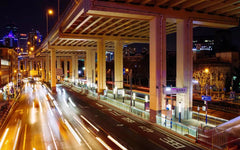 City street at night with illuminated overpass and traffic lights.