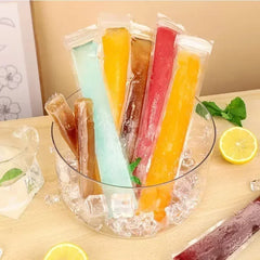 Colorful popsicles in a bowl of ice with lemons and mint leaves on a table.