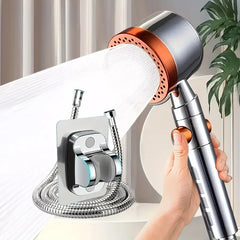 Handheld shower head with flexible hose held by a hand against a neutral background