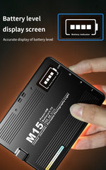 Black electronic device with battery level display screen held by a hand on a dark background