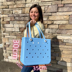 Woman holding a blue handbag with measurements against a stone wall.