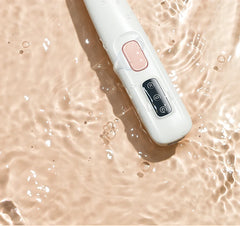 White electronic device with pink and black buttons on a wet surface