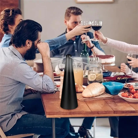 People sitting around a table with a black bottle in the foreground