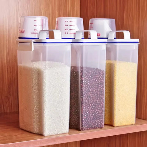 Three transparent storage containers with lids on a wooden shelf, filled with different types of grains.