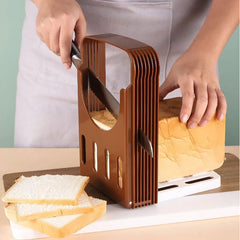 Person using a bread slicer to cut slices of bread on a wooden surface.