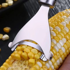 Corn shucker being used on a cob of corn with kernels scattered around.