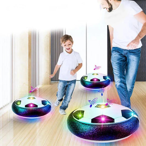 Two children playing with glowing soccer ball toys on a wooden floor.
