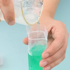 Person holding a clear container with green liquid against a light blue background