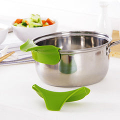 Green kitchen tool on a stainless steel pot with vegetables in the background