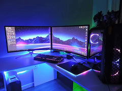 Modern computer setup with dual monitors, keyboard, and mouse on a desk with RGB lighting.
