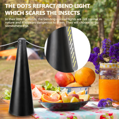 Black insect repellent device on a table with fruit and flowers outdoors