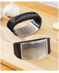 Garlic press on a wooden surface with garlic cloves