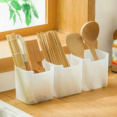 Set of wooden utensils in a white caddy on a wooden surface.