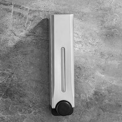Silver soap dispenser on a gray tiled wall