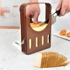 Person using a bread slicer to cut a loaf of bread on a light-colored surface.