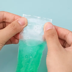 Green slime being pulled from a clear plastic bag against a light blue background