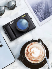 Camera, laptop, sunglasses, and coffee on a marble surface