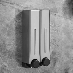Silver soap dispenser with black knobs on a gray stone wall