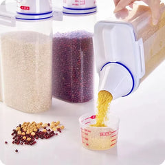 Measuring cup with a white and blue device pouring yellow grains into it, surrounded by various grains on a white surface.