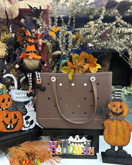 Brown handbag with Halloween-themed decorations including pumpkins and a witch.