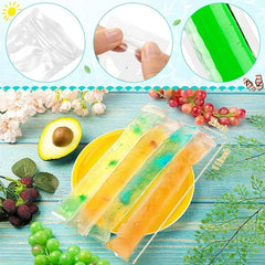 Three colorful popsicles in clear plastic wraps on a blue wooden surface with fruits and flowers.