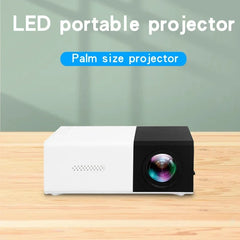 LED portable projector labeled as a palm size projector on a wooden surface with a green curtain background.
