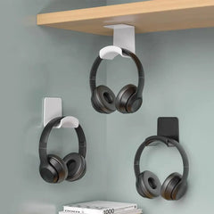 Headphone holder with three pairs of headphones hanging on a wall-mounted hook against a gray background.