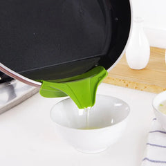 Green kitchen tool on a white surface with a pan in the background