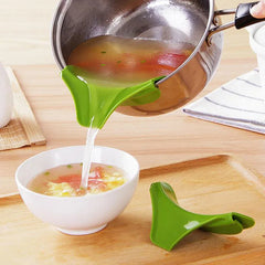 Green kitchen tool being used to pour soup from a pot into a bowl on a wooden surface.