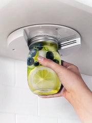 Hand holding a jar of lemonade with lemons and blueberries, attached to a car cup holder.