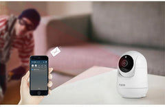 Smart home security camera and smartphone app on a table with a blurred background