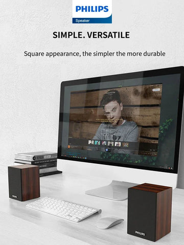 Desk setup with a computer monitor, keyboard, and speakers on a white surface.