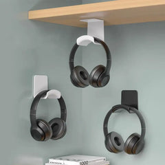 Headphone holder hanging from a shelf with three pairs of headphones.